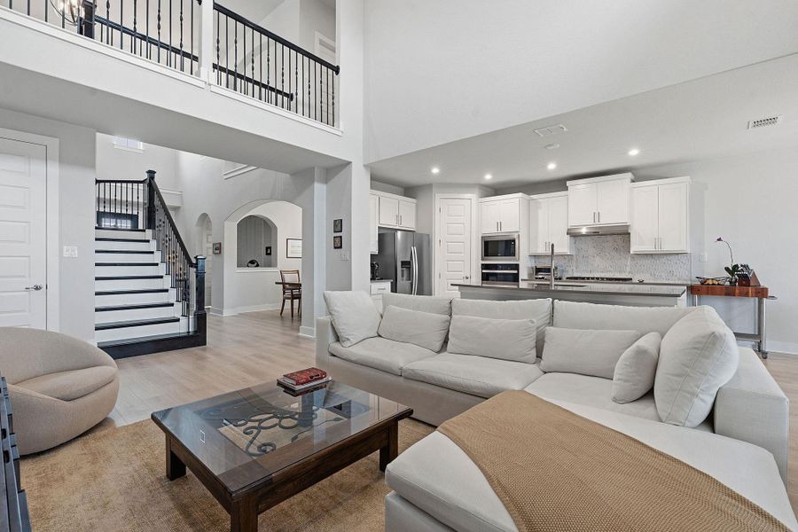 Living area with arched walkways, light wood-type flooring, recessed lighting, and a high ceiling
