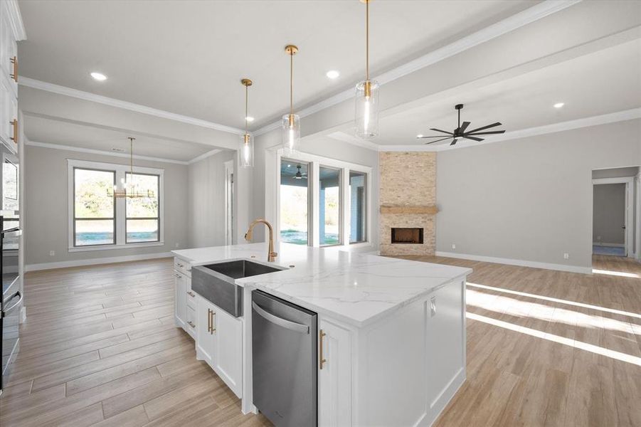 Kitchen featuring sink, hanging light fixtures, an island with sink, white cabinetry, and stainless steel appliances