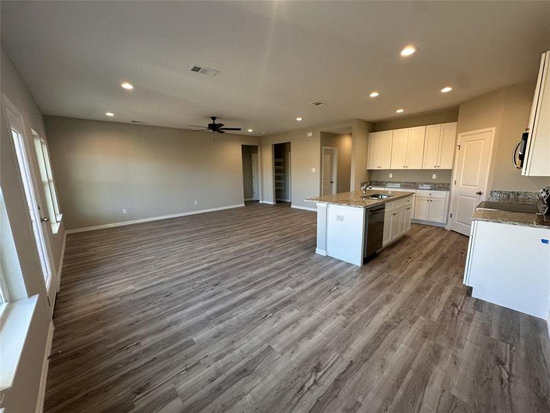 Kitchen featuring dishwasher, a kitchen island with sink, ceiling fan, white cabinetry, and wood-type flooring