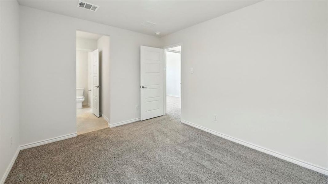 Unfurnished bedroom featuring light colored carpet and connected bathroom
