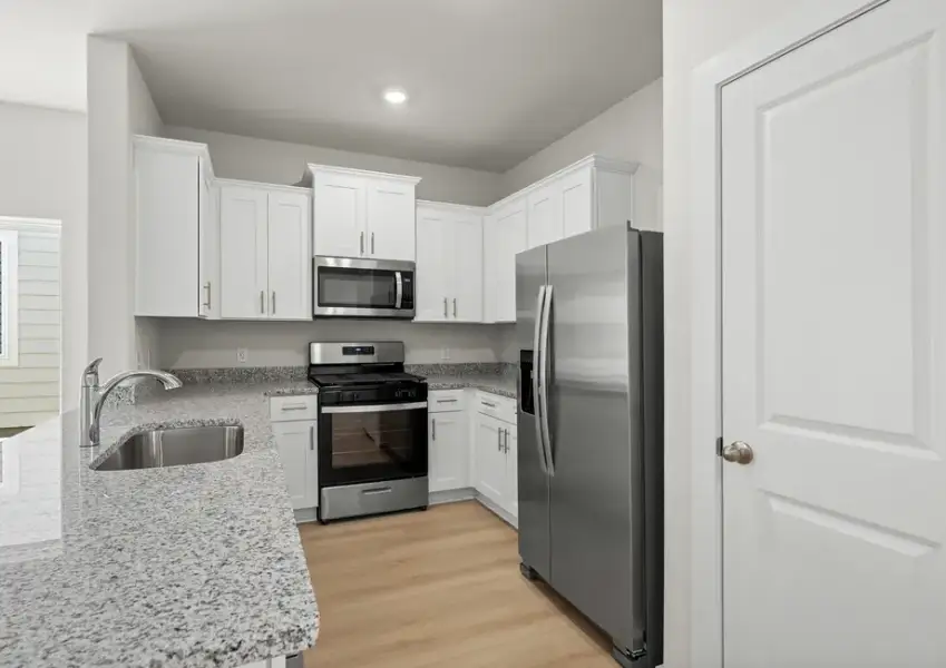Beautiful kitchen includes granite counters, white cabinetry and stainless steel Whirlpool brand appliances.