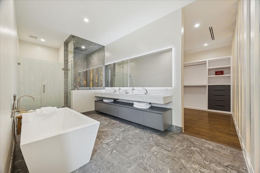 Luxurious primary bathroom with a freestanding tub featuring air jets and LED lighting, dual sinks, and a versatile walk-in shower.