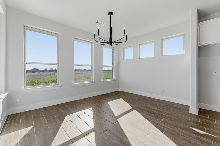 Unfurnished dining area featuring wood finish floors and a chandelier