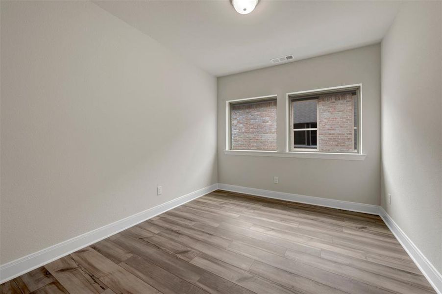 Neutral wall paint with white trim, wood-finish flooring, and two rectangular windows