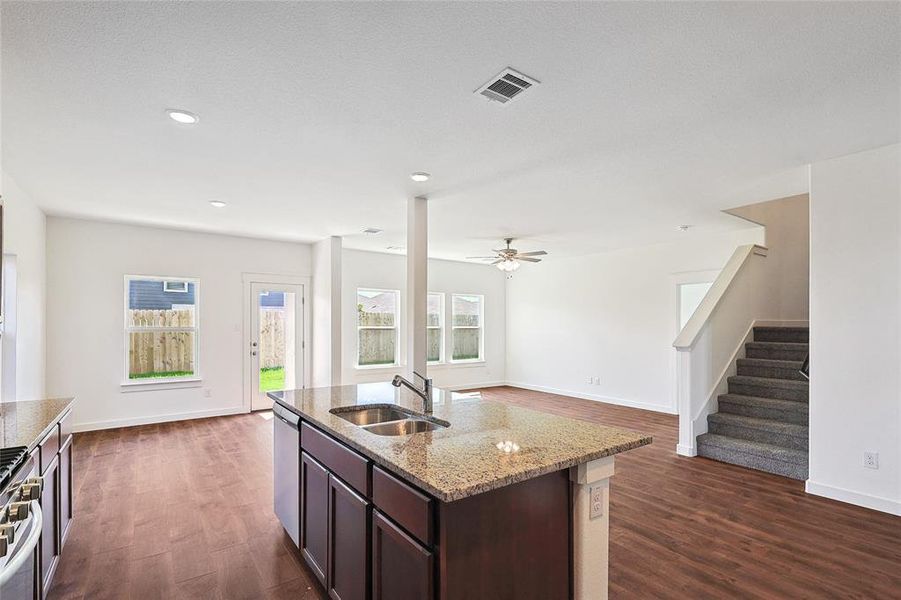 Kitchen with light stone countertops, sink, dark hardwood / wood-style flooring, appliances with stainless steel finishes, and dark brown cabinets