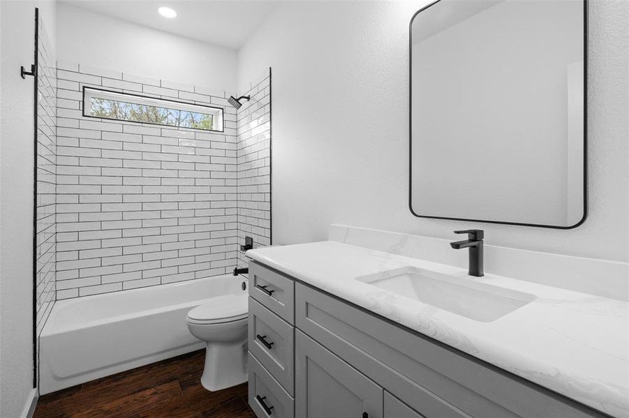 Full bath with dark wood-style floors, shower / washtub combination, and vanity
