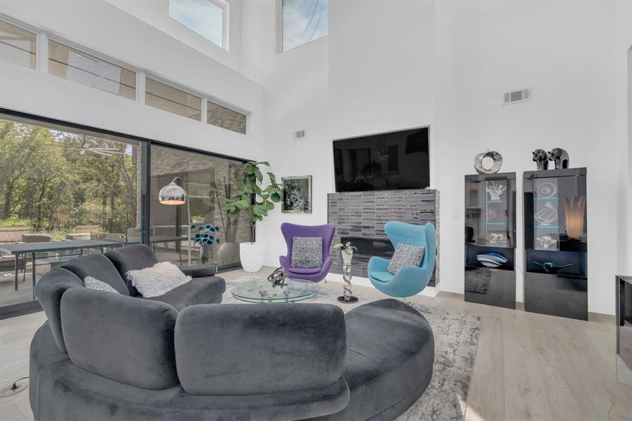 Living area with plenty of natural light, a high ceiling, and light wood finished floors