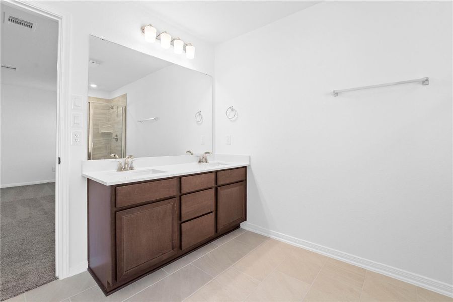 This stunningly updated primary bathroom is truly move-in ready! It features stained cabinetry with light countertops, dual vanities, a large framed mirror, a generous walk-in closet with built-in shelving, soaring ceilings, custom paint, and sleek modern finishes throughout.
