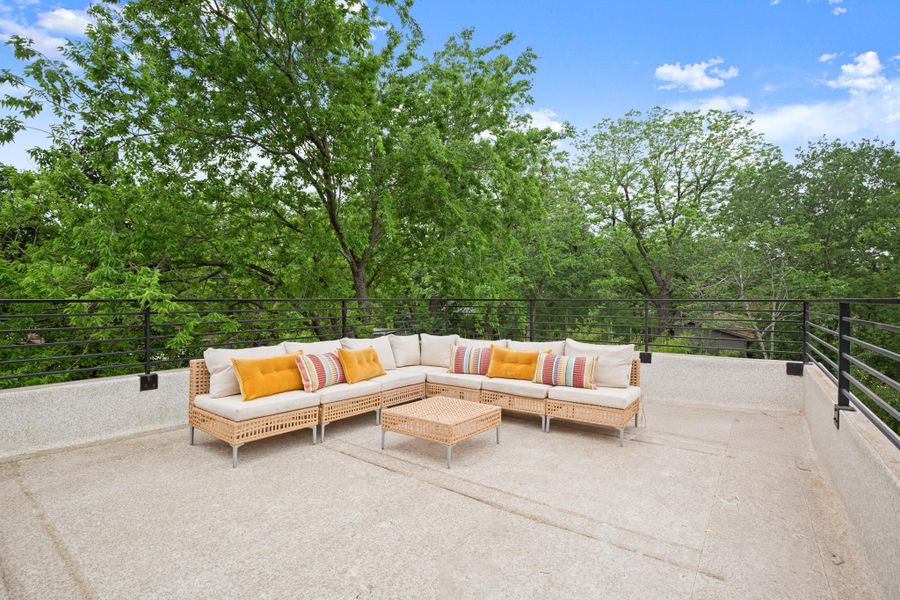 Rooftop patio with a light-colored surface and a metal railing