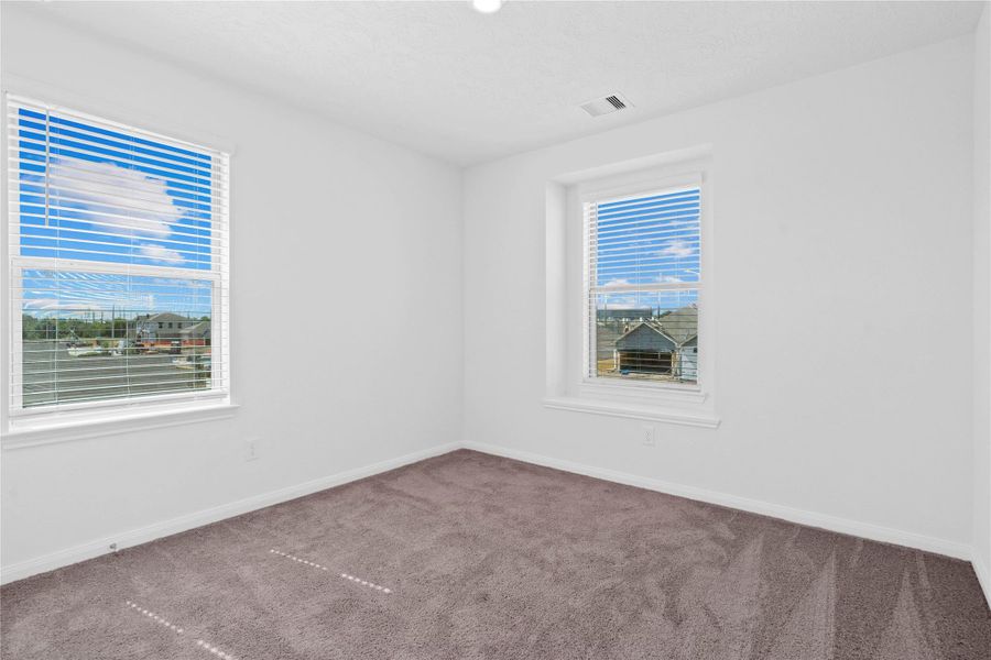 This inviting bedroom offers a bright and airy atmosphere with neutral walls, plush carpet flooring, and large windows that fills the space with natural light. This inviting bedroom offers a bright and airy atmosphere with neutral walls, plush carpet flooring, and large windows that fills the space with natural light.