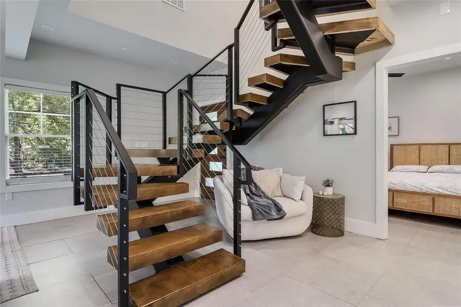 A striking modern staircase with rich wooden treads and sleek metal railings elevates this inviting entryway.