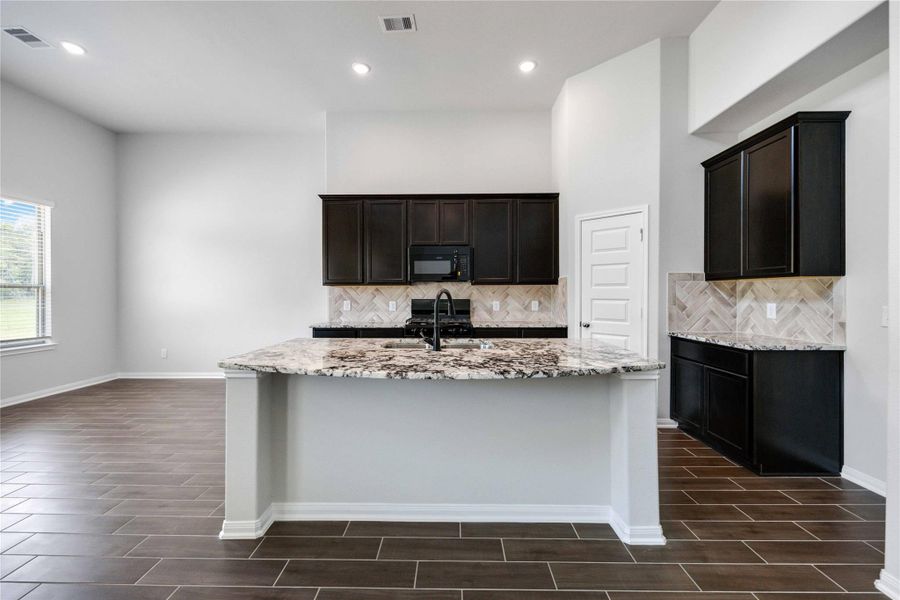 This kitchen features modern granite countertops with a matte black faucet and unique herringbone backsplash. This kitchen is sure to impress!