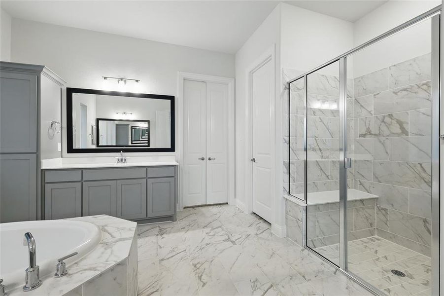 Full bathroom featuring a shower stall, a bath, marble finish flooring, and vanity