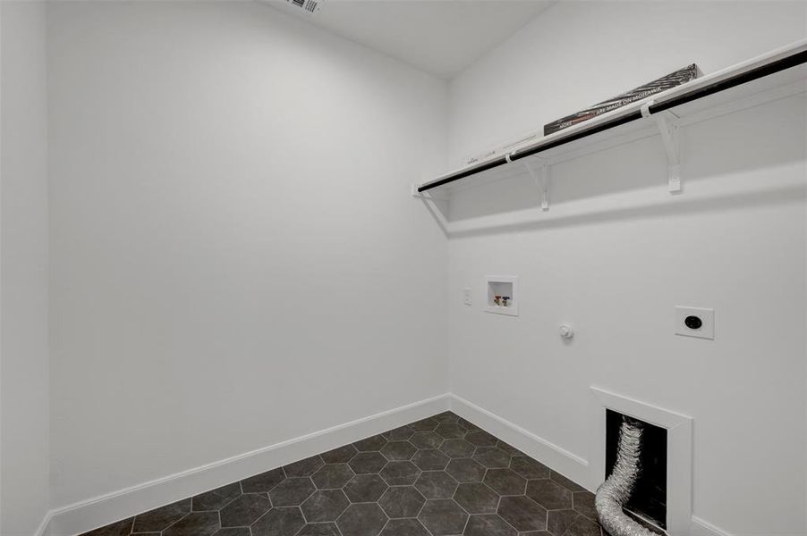 Utility room featuring hexagonal floor tiles, a wall-mounted shelf with a hanging rod, and utility hookups
