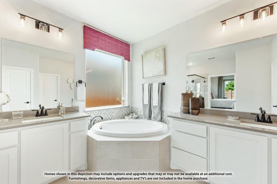 Master bathroom with soaking tub, dual vanities, white cabinets, and mosaic tile surround