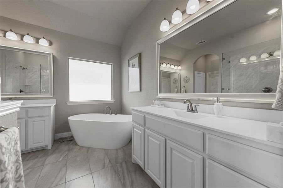 Bathroom featuring shower with separate bathtub, vanity, and vaulted ceiling