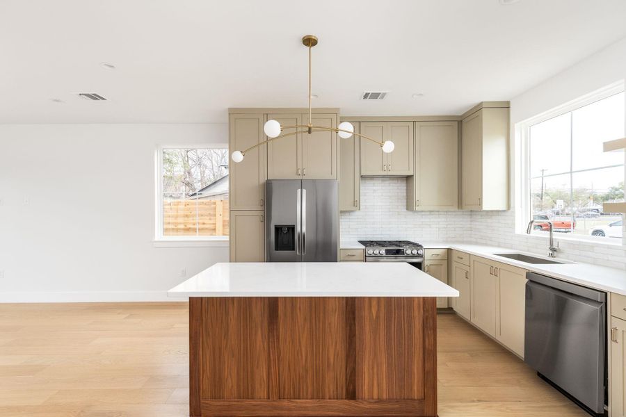 Kitchen with cream cabinetry, stainless steel appliances, a kitchen island, and light wood-style floors