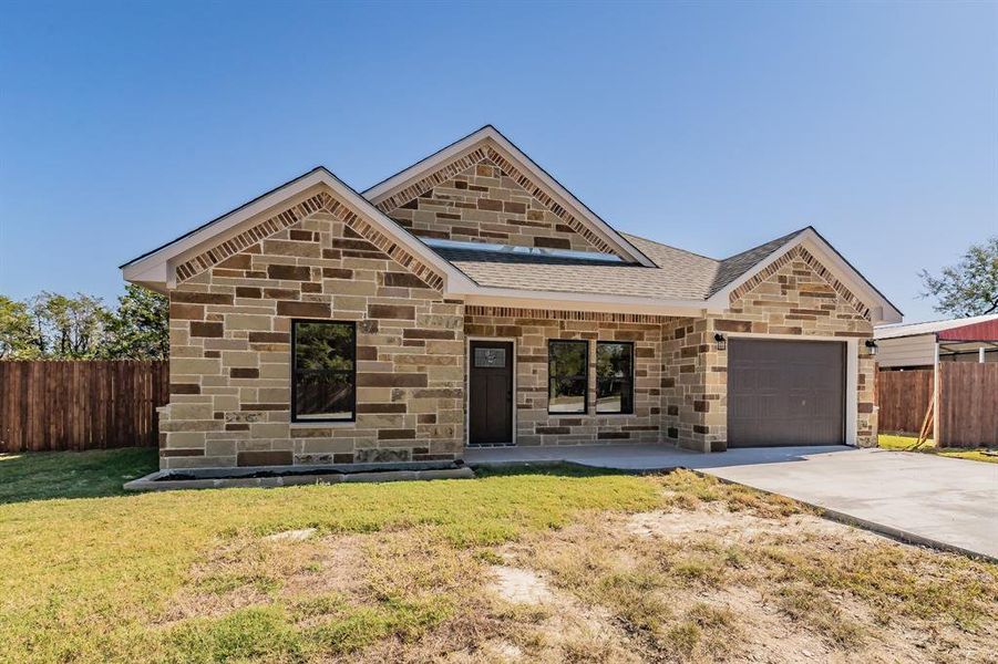 View of front of house featuring stone siding, covered porch, driveway, and a garage