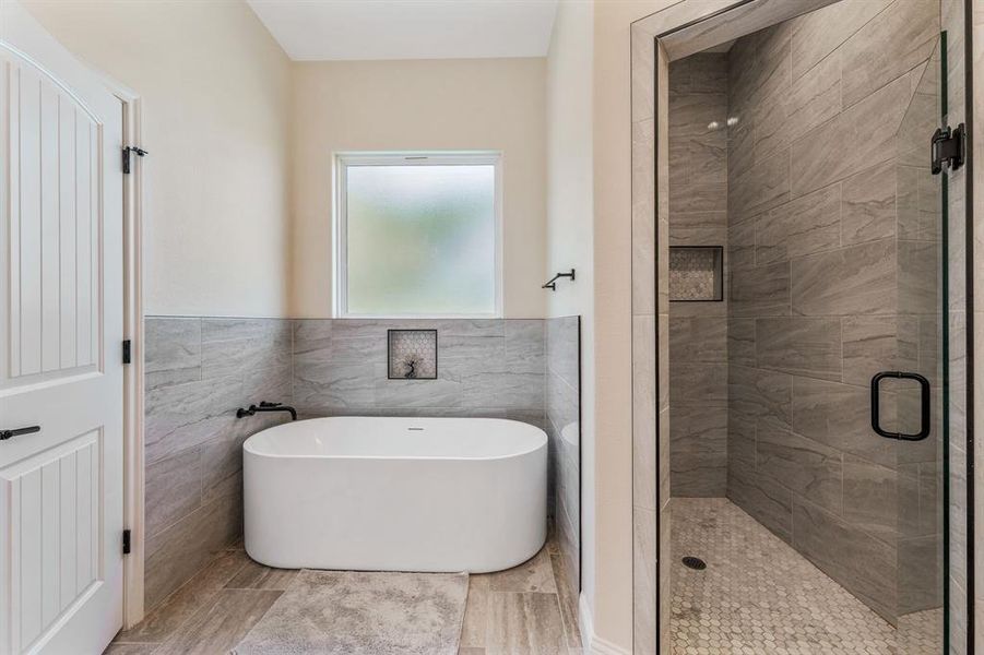 Bathroom with tile walls, a stall shower, a soaking tub, and wainscoting Bathroom with tile walls, a stall shower, a soaking tub, and wainscoting