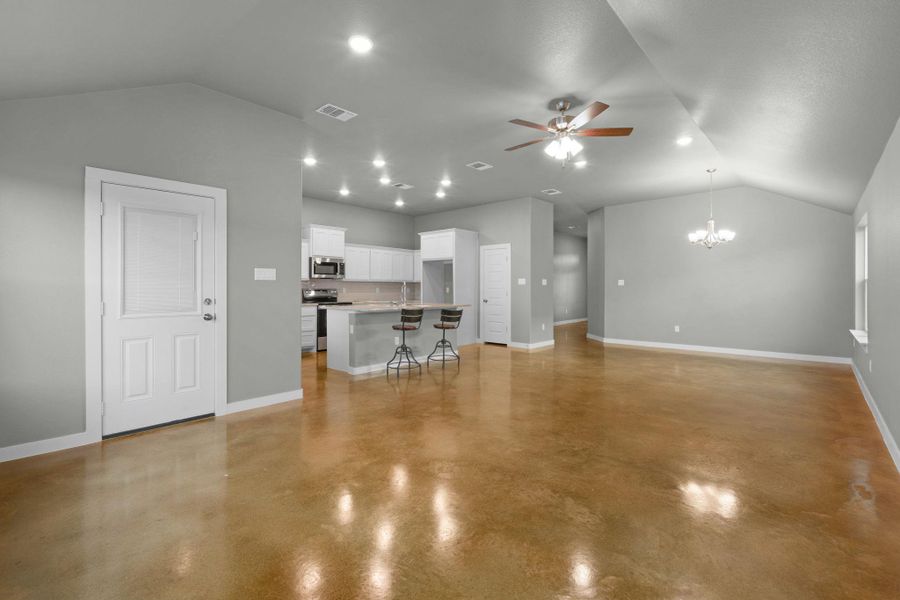 An open-concept living space with lustrous concrete flooring and a well-appointed kitchen.