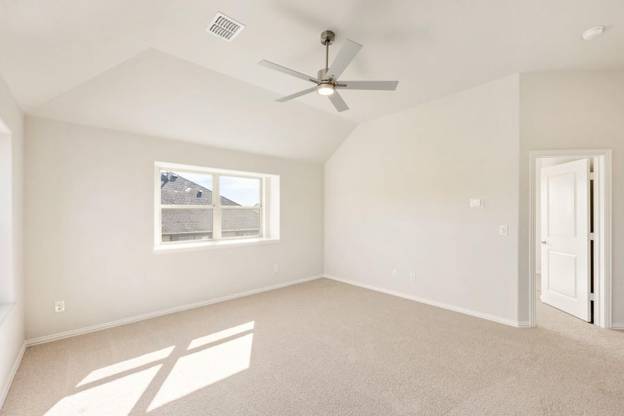 Empty bedroom with vaulted ceiling, ceiling fan, carpet flooring, and a single window Empty bedroom with vaulted ceiling, ceiling fan, carpet flooring, and a single window