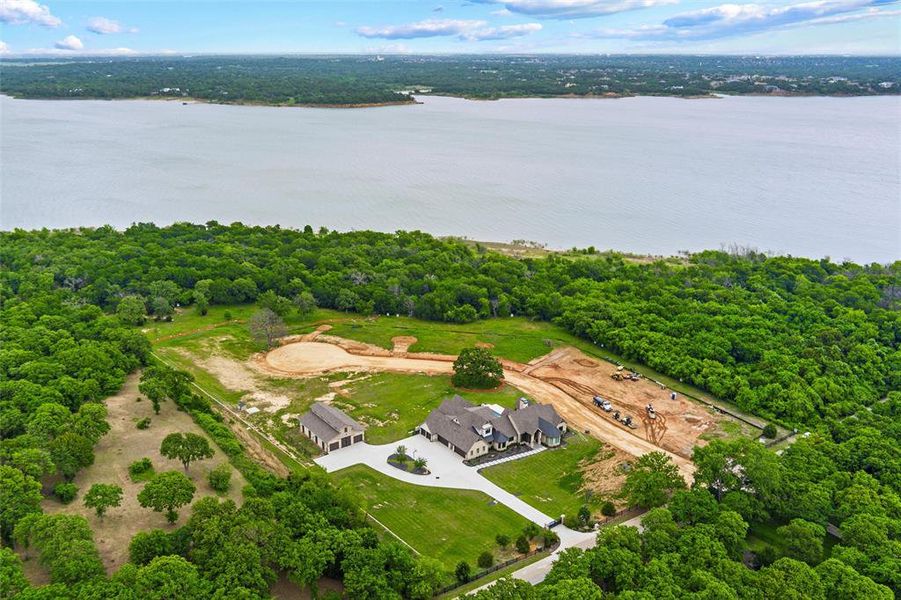 Expansive waterfront property featuring a large residence, detached garage, extensive green space, and mature tree coverage Expansive waterfront property featuring a large residence, detached garage, extensive green space, and mature tree coverage
