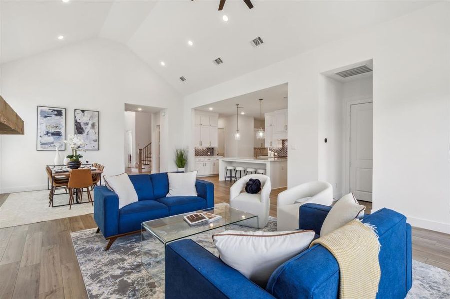 Living room with ceiling fan, light hardwood / wood-style floors, sink, and high vaulted ceiling