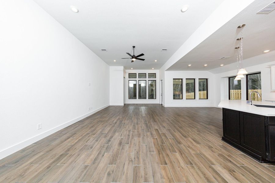 Enjoy the open and airy Family Room, designed for seamless entertaining and showcasing striking architectural details with large tall windows, high ceilings with ceiling fan, recessed lighting, and durable flooring.