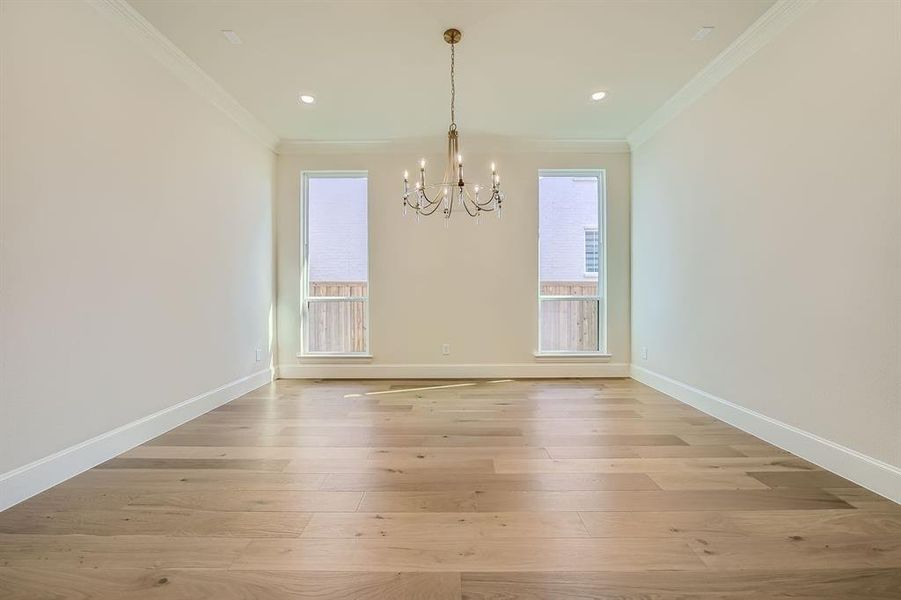 Large dining area featuring light wood-type flooring, a chandelier, and crown molding