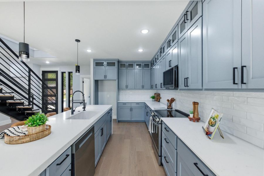 Kitchen with stainless steel appliances, light wood-type flooring, decorative light fixtures, backsplash, and recessed lighting Kitchen with stainless steel appliances, light wood-type flooring, decorative light fixtures, backsplash, and recessed lighting