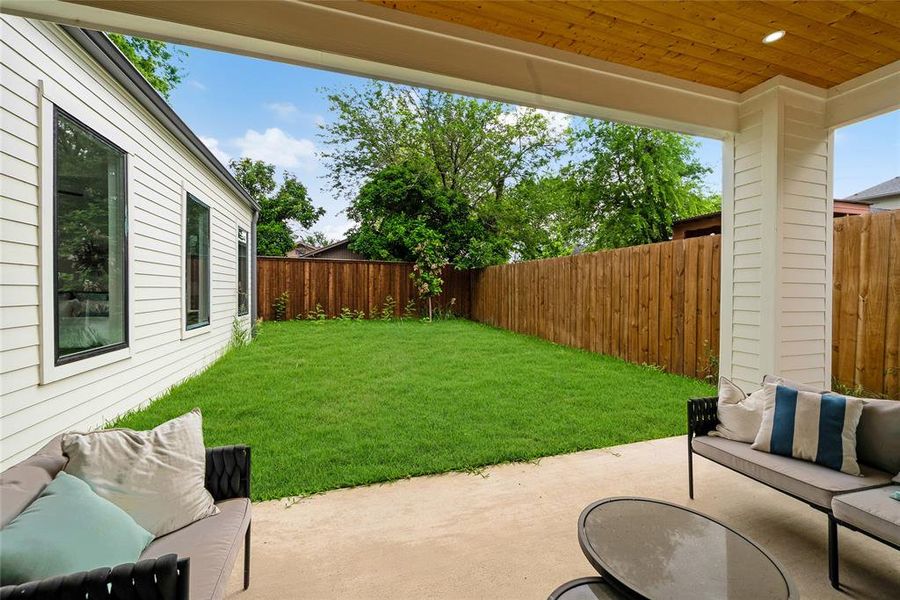 The property features a spacious rear yard with a well-maintained lawn, enclosed by a wooden fence