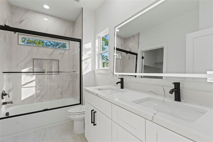 Full bathroom with combined bath / shower with glass door, double vanity, and recessed lighting
