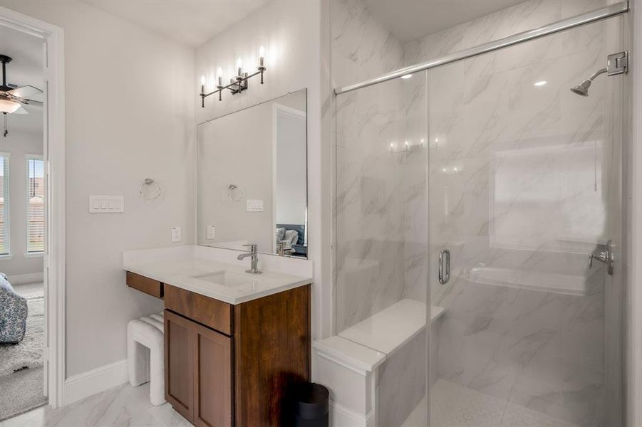 The primary bathroom has a walk-in shower with upgraded tile surround extended to ceiling, framless glass door, bench, and mudset flooring.