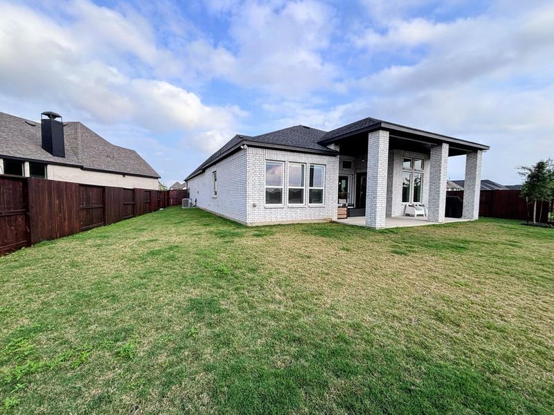 Spacious backyard with a well-maintained lawn and a covered patio area.