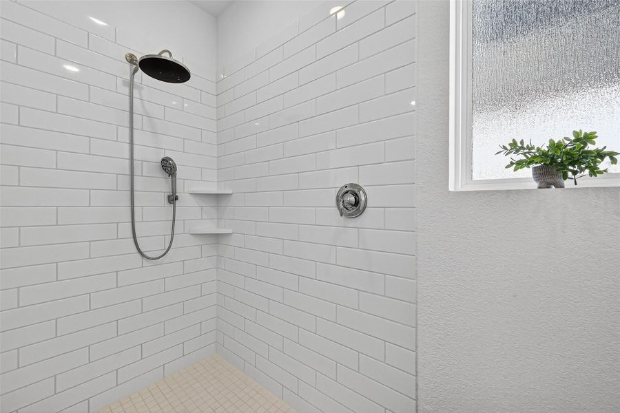 Luxurious primary bathroom featuring a sleek, modern shower with elegant white tile and natural light. Luxurious primary bathroom featuring a sleek, modern shower with elegant white tile and natural light.