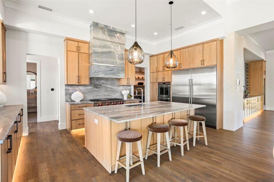 This kitchen features a custom quartz hood, oak cabinets and ample space for cooking.