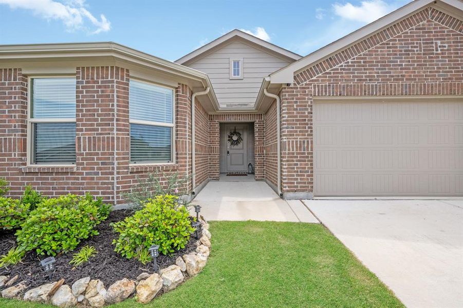 Ranch-style house with an attached garage, concrete driveway, brick siding, and a front yard
