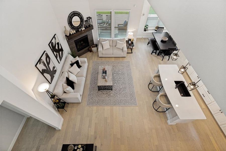 Open-concept living space with light wood-finish flooring, a contemporary fireplace with dark wood surround, and white walls