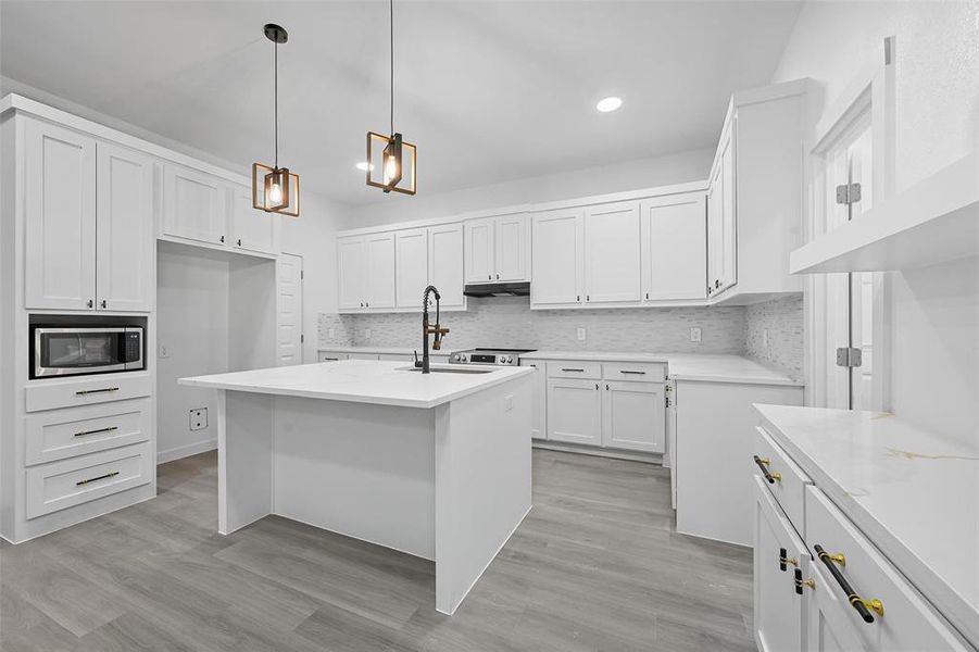 Kitchen with tasteful backsplash, white cabinets, hanging light fixtures, and recessed lighting Kitchen with tasteful backsplash, white cabinets, hanging light fixtures, and recessed lighting