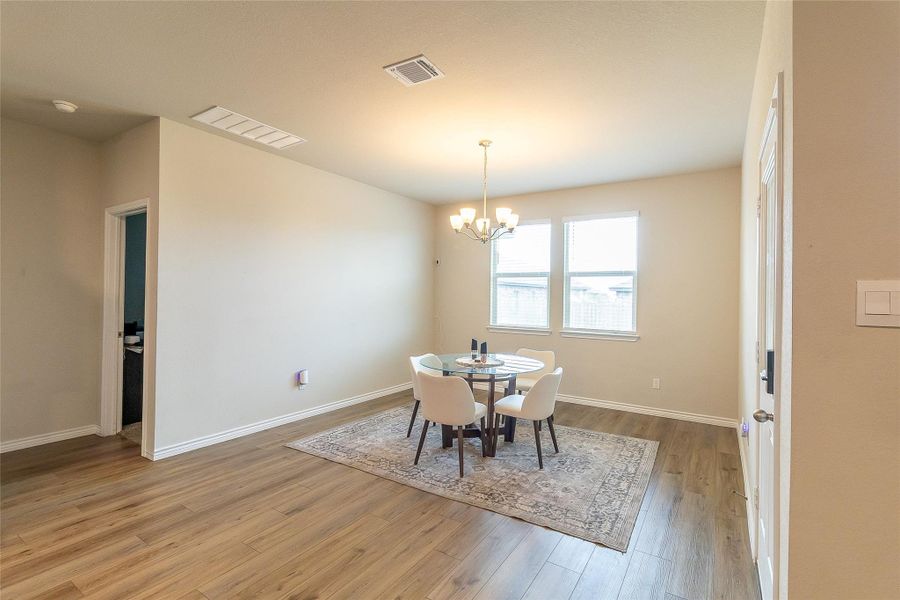 A well-lit dining area features polished wood flooring and ample natural illumination from twin windows.