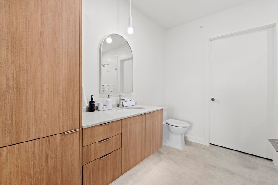The primary bath pairs light wood tones with quartz surfaces and a glass enclosed shower for a bright, calming atmosphere. The primary bath pairs light wood tones with quartz surfaces and a glass enclosed shower for a bright, calming atmosphere.