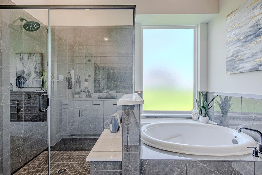 Enjoy spa-like luxury with a deep soaking tub and a sleek glass-enclosed shower wrapped in rich stone tile.