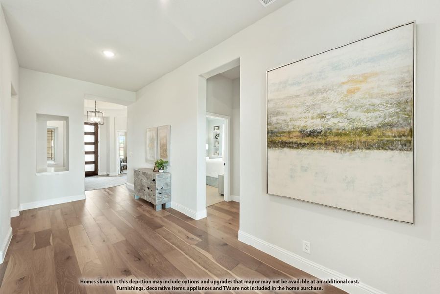 Bright hallway with hardwood floors, white walls, large wall art, and view to front entry with pendant light Bright hallway with hardwood floors, white walls, large wall art, and view to front entry with pendant light