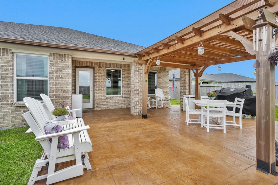 This photo showcases a spacious backyard patio with a wooden pergola, perfect for outdoor entertaining.