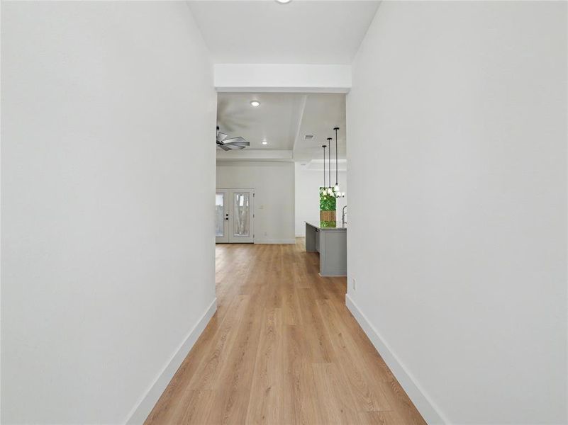 Hallway entry featuring wood-finish flooring, white walls, and a recessed ceiling light Hallway entry featuring wood-finish flooring, white walls, and a recessed ceiling light