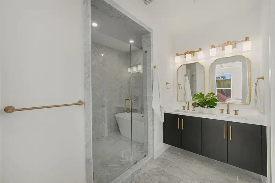 Modern bathroom featuring a double vanity with dark cabinetry and gold-tone hardware Modern bathroom featuring a double vanity with dark cabinetry and gold-tone hardware