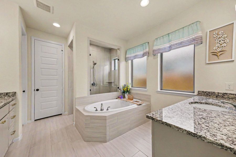 Lavish primary bathroom with dual vanities, a soaking tub, a glass-standing shower, and a massive walk-in closet. Lavish primary bathroom with dual vanities, a soaking tub, a glass-standing shower, and a massive walk-in closet.