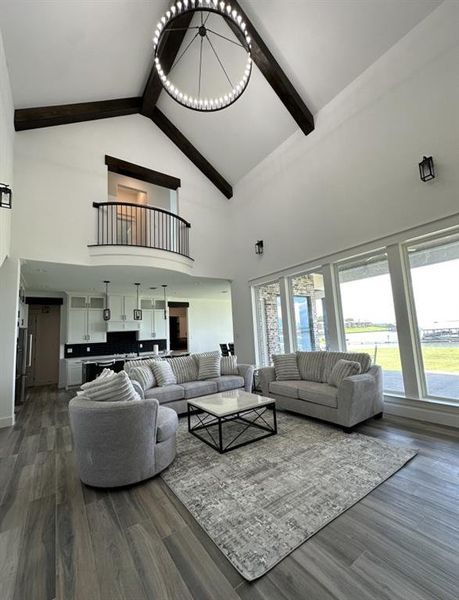 Living room featuring high vaulted ceiling, beamed ceiling, dark wood-type flooring, a chandelier, and plenty of natural light Living room featuring high vaulted ceiling, beamed ceiling, dark wood-type flooring, a chandelier, and plenty of natural light