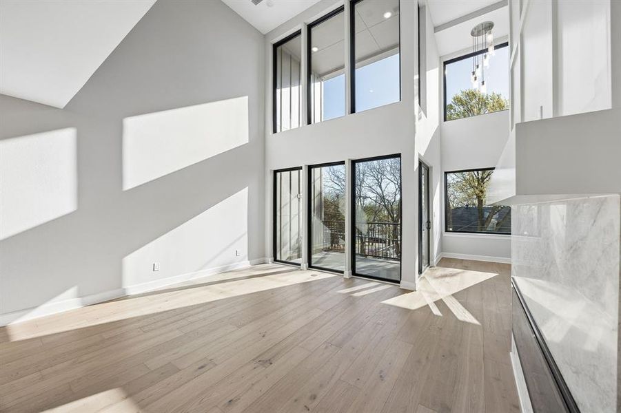 Unfurnished living room featuring light wood-style flooring and lofted ceiling Unfurnished living room featuring light wood-style flooring and lofted ceiling