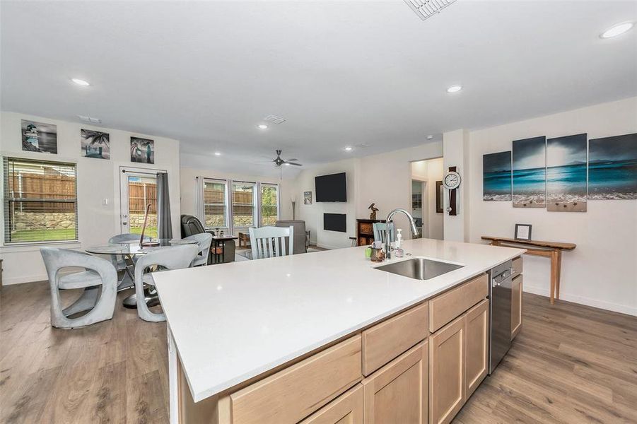 Kitchen featuring light brown cabinets, ceiling fan, an island with sink, sink, and wood-type flooring